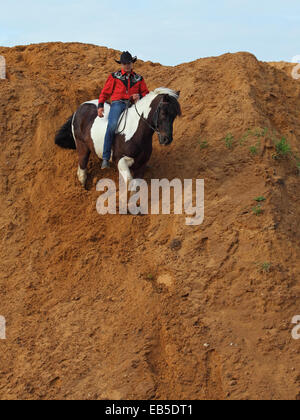 Dans l'homme vêtements cowboy rides bareback sur un cheval repéré sur une colline de sable Banque D'Images
