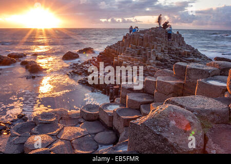 Les personnes qui désirent visiter Giant Causeway s au coucher du soleil dans le Nord d'Antrim, en Irlande du Nord Banque D'Images