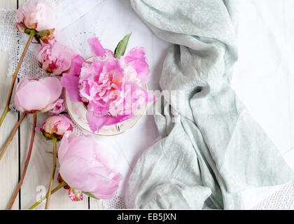 Création d'un arrangement de rose sur Sarah Bernhardt pivoines sur la table, une fleur dans un verre d'vintage sur tissu dentelle blanche Banque D'Images