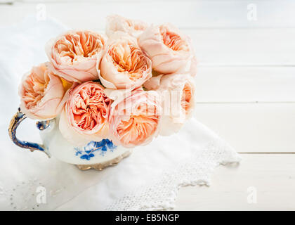 Bouquet de roses David Austin 'Juliet' dans une théière bleu et blanc vintage Banque D'Images