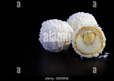 Truffes au chocolat blanc et noix de coco sur fond noir Banque D'Images