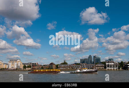 Bateau remorqueur tirant plein de conteneurs barge sur la Tamise avec Canary Wharf à l'arrière-plan Banque D'Images