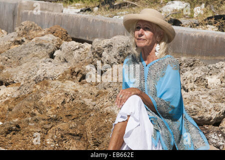 Mature Woman sitting on rocks au Beer pouvez Island, Longboat Key, Florida, USA Banque D'Images