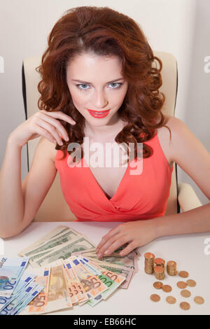 Belle femme d'affaires en robe rose sur table sont les billets d'Euro et USD Banque D'Images