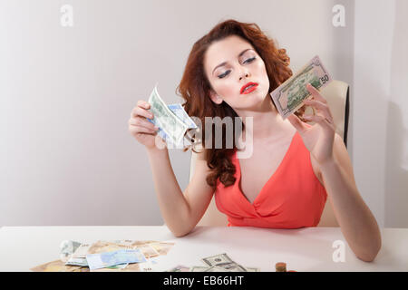 Belle femme d'affaires en robe rose sdet à table sur laquelle l'argent Banque D'Images