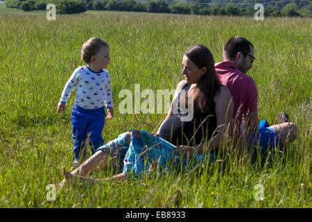 Une famille heureuse, une femme enceinte avec son mari et petit garçon passer du temps ensemble et de jouer à des jeux dans une prairie d'été Banque D'Images