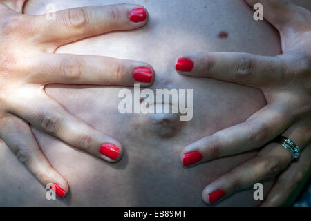 Bouton du ventre de femme enceinte, gros doigts touchant Banque D'Images