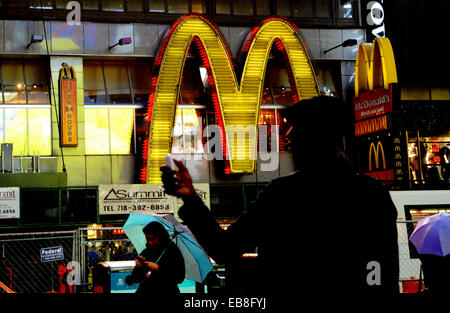 Times Square de nuit avec des personnes à l'aide de leur téléphone mobile en face de McDonald's restaurant fast food New York USA Banque D'Images