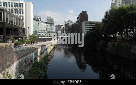 Vue du ciel bleu, les arbres de l'Albert Bridge Passerelle Trinity, bâtiments reflétant rivière Irwell par riverside walkway, Manchester Banque D'Images