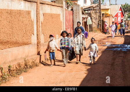 Les enfants africains à marcher le long d'une rue non goudronnée à Antananarivo, ou Tana, capitale de Madagascar Banque D'Images