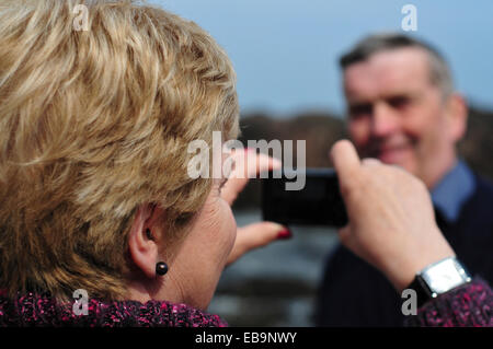 Woman Taking Photo of Man with Smart Phone