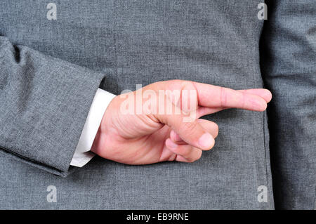 Un homme portant un costume croisant les doigts dans son dos Banque D'Images