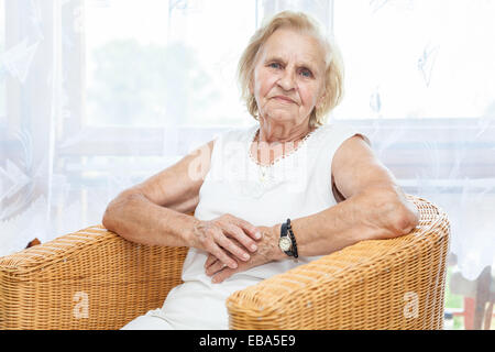 Portrait d'une vieille dame dans son 70s'asseoir sur une chaise Banque D'Images