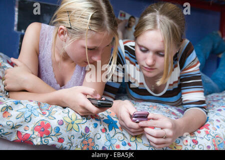 Teenage Girls looking at leur téléphone mobile dans leur chambre à coucher, Banque D'Images