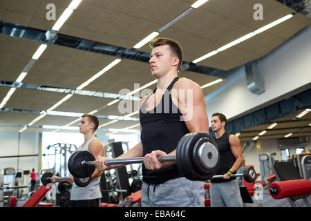 Groupe d'hommes flexing muscles avec barbell in gym Banque D'Images