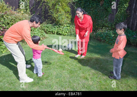 Jeune famille à jouer avec une raquette et balle dans le jardin, Banque D'Images