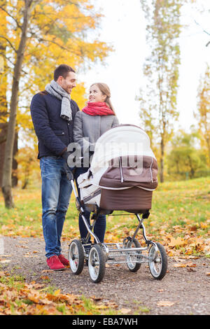 Smiling couple avec bébé la pram in autumn park Banque D'Images