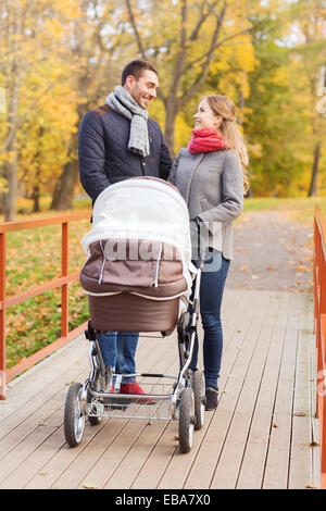 Smiling couple avec bébé la pram in autumn park Banque D'Images