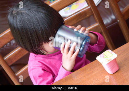 Petite fille ayant un verre à partir d'une tasse en plastique, Banque D'Images