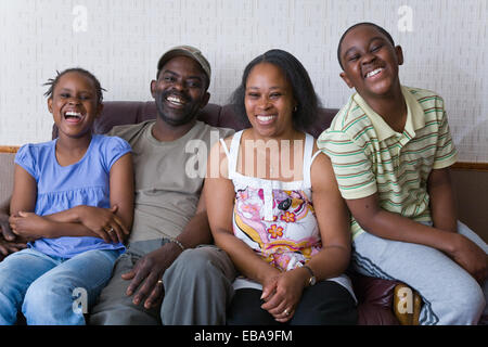 Famille assise sur le canapé en riant, Banque D'Images