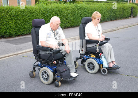 Mobilité couple traverser la route en fauteuil roulant motorisé, Banque D'Images