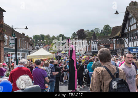 Un homme en haut de forme et sur pilotis divertit les foules dans la rue principale à Haslemere pour la Charte juste. Banque D'Images