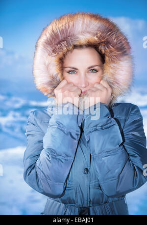 Closeup portrait of mignon femelle à l'extérieur en hiver, porter décontracté élégant manteau bleu avec capuche à fourrure, mode hiver Banque D'Images