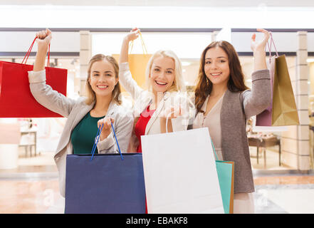 Heureux les jeunes femmes avec shopping bags in mall Banque D'Images