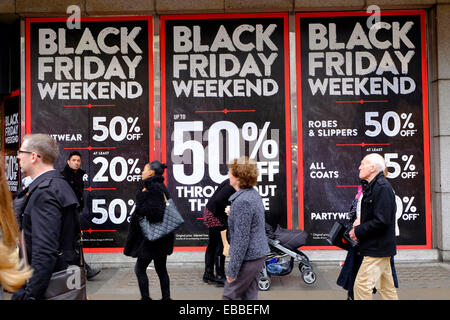 Shoppers passons un grand magasin avec des panneaux indiquant 'Black week-end Vendredi, 50 % off'. Oxford Street, Londres Banque D'Images