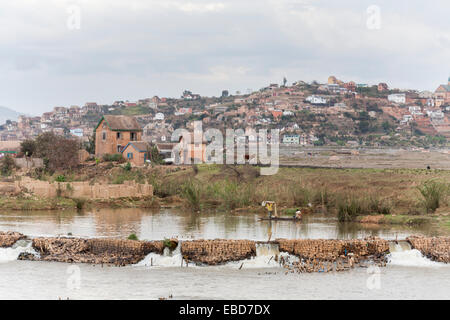 Vie locale : Lac avec barrage de brique pour les pêcheurs locaux et de banlieue bidonville scène à Antananarivo, ou Tana, capitale de Madagascar Banque D'Images