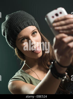 Portrait of Teenage Girl en tenant avec Selfies Cell Phone, Studio Shot Banque D'Images