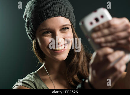 Portrait of Teenage Girl en tenant avec Selfies Cell Phone, Studio Shot Banque D'Images