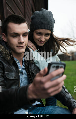 Close-up of young man and woman outdoors, looking at cell phone, Allemagne Banque D'Images