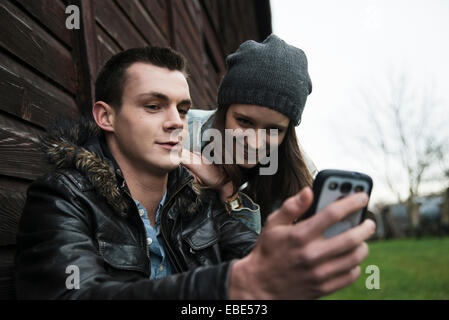 Close-up of young man and woman outdoors, looking at cell phone, Allemagne Banque D'Images