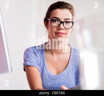 Portrait of young woman in office, le port de lunettes cerclées de corne et looking at camera, Allemagne Banque D'Images