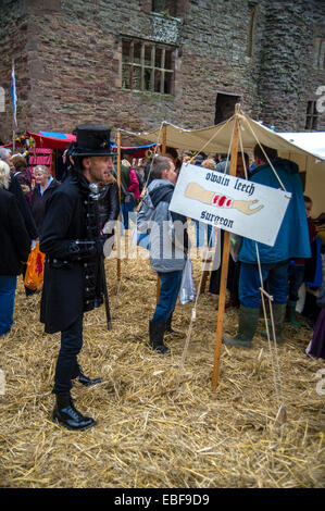 Un homme en costume à la recherche d'un signe pour le leech chirurgien au Ludlow Castle Noël Nourriture et foire artisanale. Banque D'Images