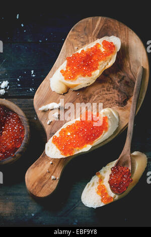 Des sandwichs avec du caviar rouge servi sur une planche à découper en bois d'olivier plus vieille table en bois. Vue d'en haut. Voir la série Banque D'Images