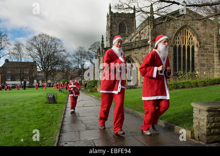 Les personnes (hommes, femmes et enfants) vêtus de rouge et blanc Père Noël tenues sont la marche, le jogging, la course et de prendre part à la grande Skipton Santa Fun Run, une course de bienfaisance annuelle de collecte de fonds organisé par le Rotary Club - centre-ville de Skipton, Yorkshire du Nord, Angleterre, Royaume-Uni. Banque D'Images