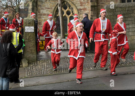 Les personnes (hommes, femmes et enfants) vêtus de rouge et blanc Père Noël tenues sont la marche, le jogging, la course et de prendre part à la grande Skipton Santa Fun Run, une course de bienfaisance annuelle de collecte de fonds organisé par le Rotary Club - centre-ville de Skipton, Yorkshire du Nord, Angleterre, Royaume-Uni. Banque D'Images