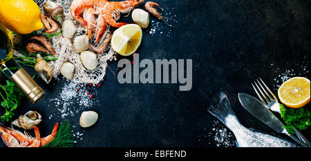 Délicieux poissons frais et fruits de mer sur fond foncé vintage. Les poissons, les coques et les crevettes avec des herbes aromatiques, épices et légumes Banque D'Images