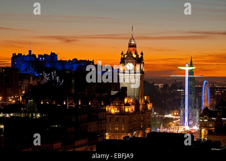 Edinburgh, Ecosse, Royaume-Uni. 30 novembre, 2014. Le Château d'Édimbourg et la ville vue depuis Calton Hill au coucher du soleil le château est illuminé par l'éclairage bleu lors de la fête de St Andrew, montrant également La Grande Roue et Star Flyer manèges situés à côté du Scott Monument dans les jardins de Princes Street à l'Est. Banque D'Images