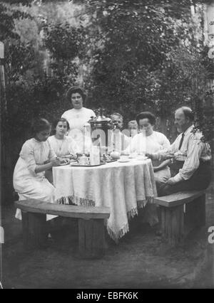 Dans le jardin. Famille assis à une table ronde avec un samovar. La photographie rétro, Russie, vers 1905 Banque D'Images