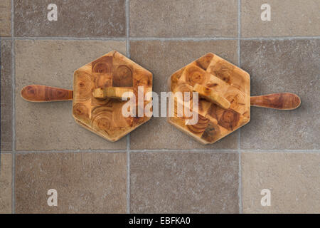 Deux pots de condiments en bois avec des cuillères et des couvercles sur un sol dallé Banque D'Images