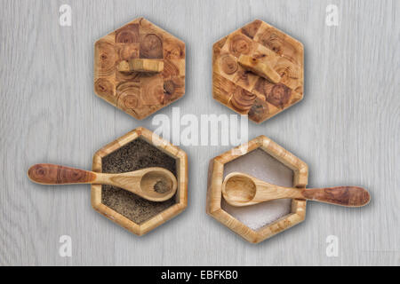 Deux pots de condiments en bois avec des cuillères et des couvercles sur une table en bois Banque D'Images