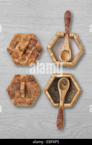 Deux pots de condiments en bois avec des cuillères et des couvercles sur une table en bois Banque D'Images