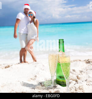 Heureux couple celebrating Christmas with champagne on beach Banque D'Images