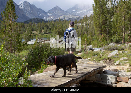 Une femme avec un chien de randonnée le long de la vallée des lacs peu de Rock Creek dans les montagnes de la Sierra Nevada en Californie USA Banque D'Images