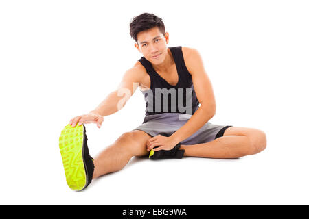 Smiling young man sitting remise en forme et de faire des exercices d'étirement Banque D'Images