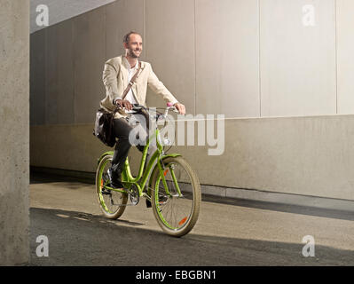 Homme portant un sac sur son épaule, tout en faisant du vélo dans la ville, Innsbruck, Tyrol, Autriche Banque D'Images