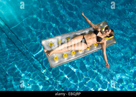 Jeune femme sur matelas d'air dans une piscine, Autriche Banque D'Images